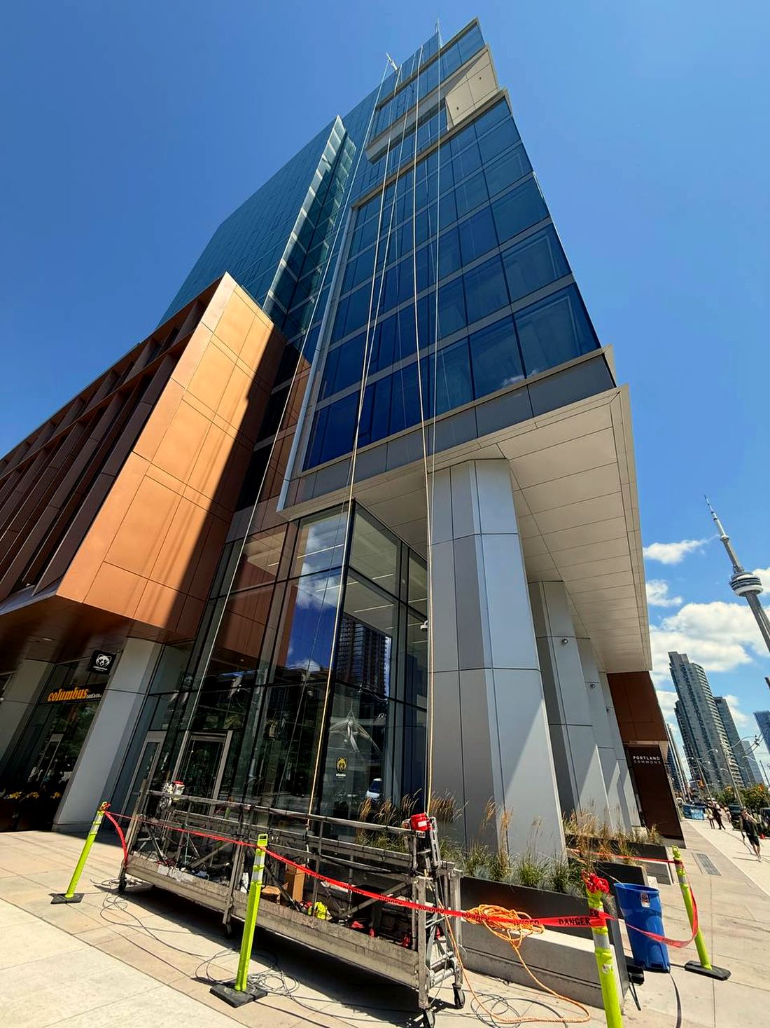 PGM Glass & Mirrors swing-stage high-rise glazing on a commercial tower in Toronto, CN Tower in the background